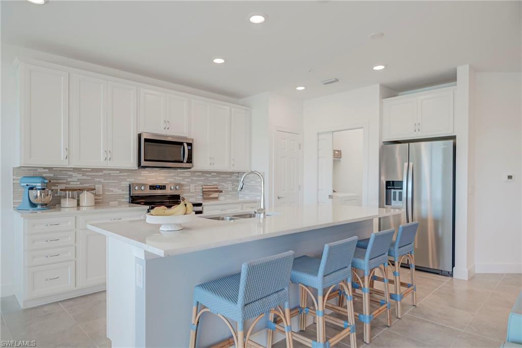 5686 Mayflower Way, Unit 702 Ave Maria, FL 34142 - Photo 12 of 50 Kitchen with stainless steel appliances, recessed lighting, a kitchen breakfast bar, white cabinets, and a kitchen island with sink