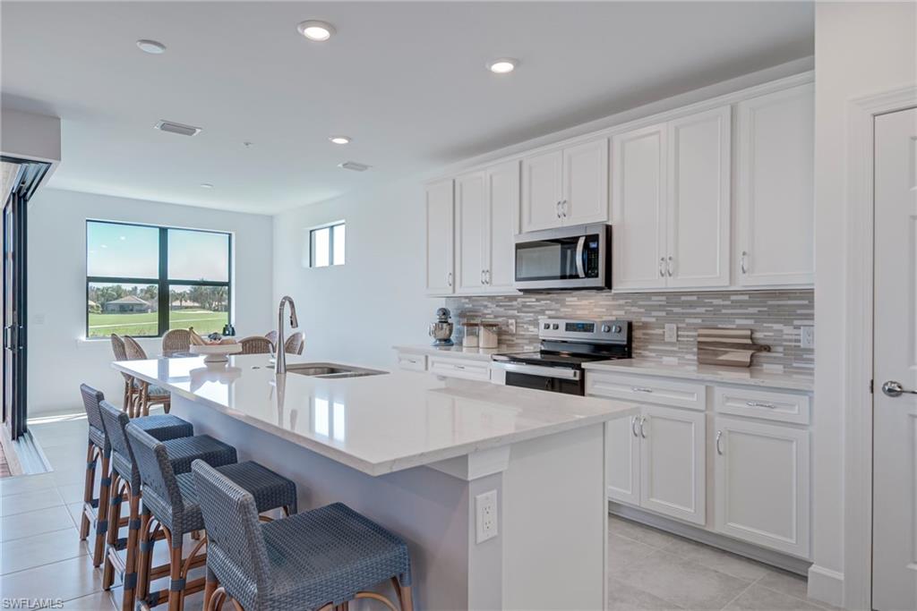 5686 Mayflower Way, Unit 702 Ave Maria, FL 34142 - Photo 13 of 50 Kitchen with stainless steel appliances, white cabinetry, a kitchen snack bar, and recessed lighting
