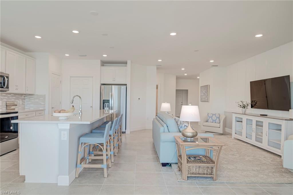 5686 Mayflower Way, Unit 702 Ave Maria, FL 34142 - Photo 50 of 50 Kitchen featuring an island with double stainless sink, white cabinets, stainless steel appliances, open floor plan, and a kitchen bar