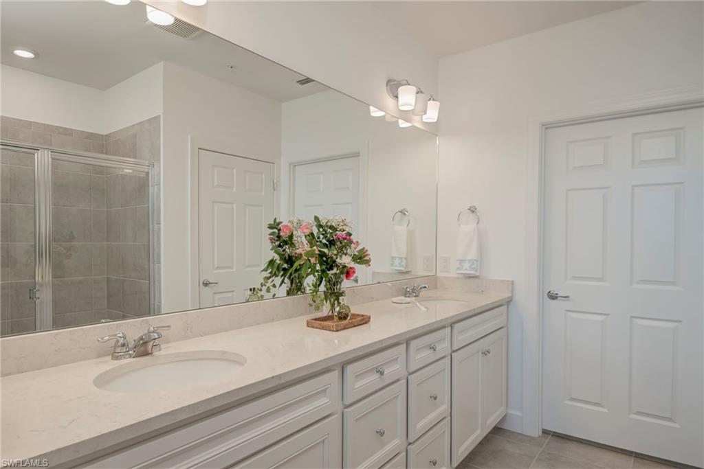 5686 Mayflower Way, Unit 702 Ave Maria, FL 34142 - Photo 19 of 50 Master bath featuring double vanity, a walk-in shower, and plenty of cupboards and drawer space