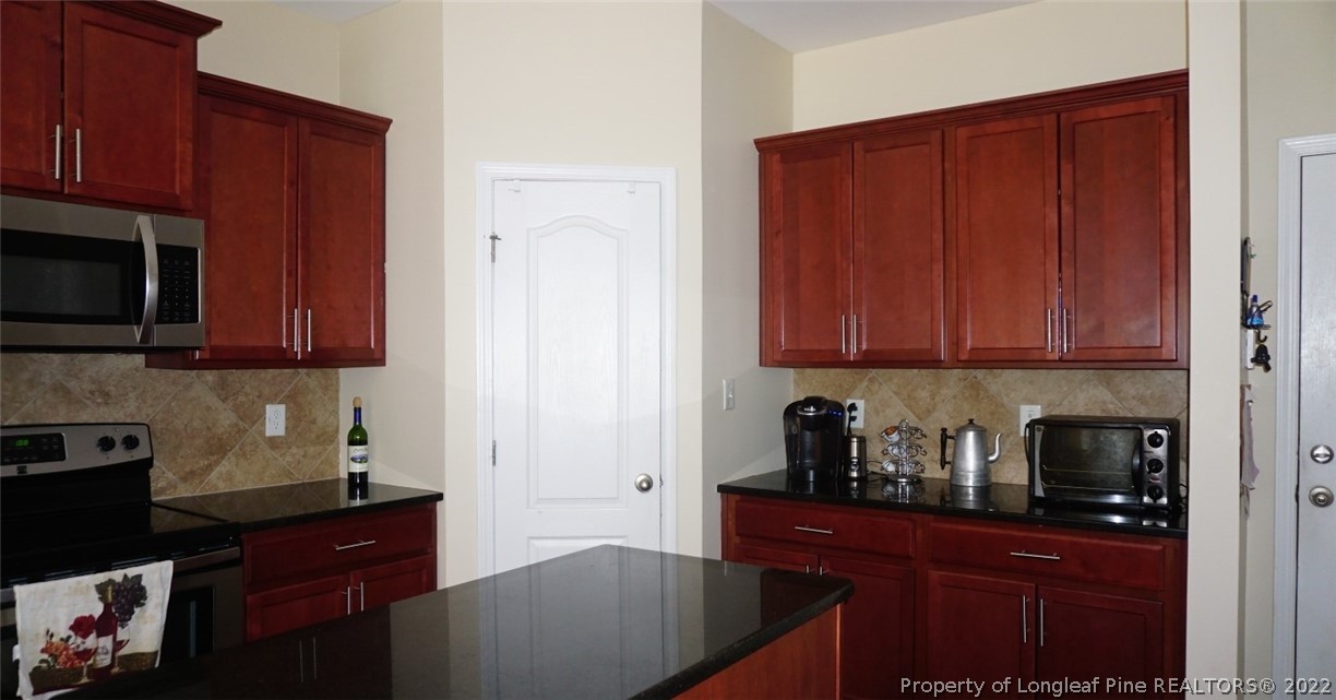 115 Shellbark Drive Spring Lake, NC 28390 - Photo 10 of 30 a kitchen with stainless steel appliances granite countertop wooden cabinets a stove top oven a sink and dishwasher