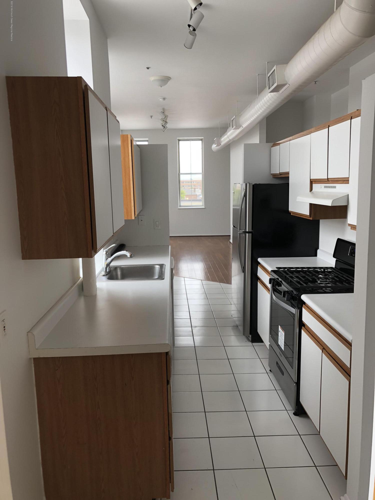 40 Broad Street, Unit 3A Red Bank, NJ 07701 - Photo 5 of 10 a kitchen with kitchen island granite countertop a sink appliances and cabinets