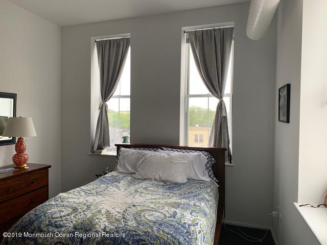 40 Broad Street, Unit 3A Red Bank, NJ 07701 - Photo 7 of 10 a bedroom with a bed wooden floor and a large window