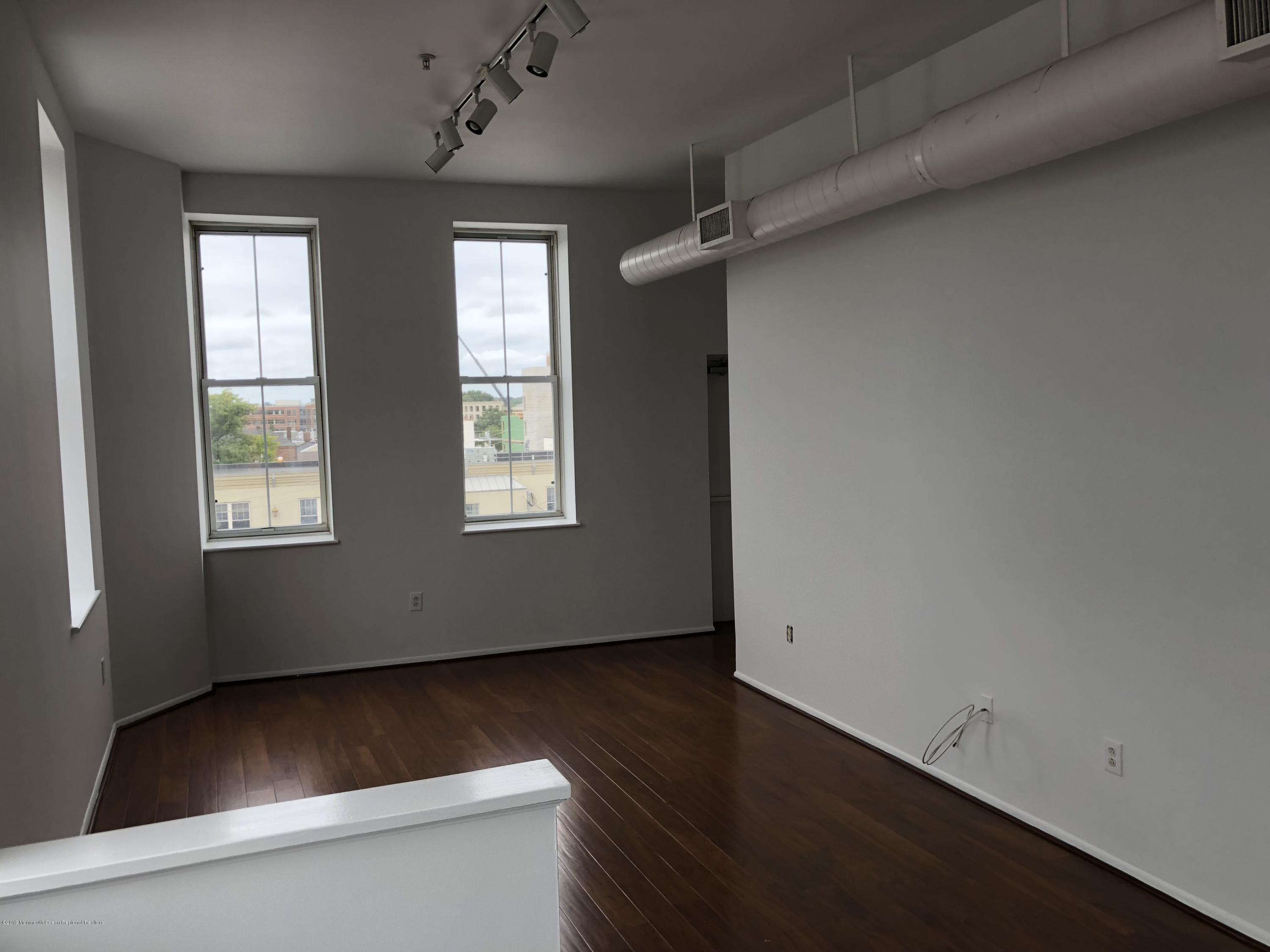 40 Broad Street, Unit 3A Red Bank, NJ 07701 - Photo 9 of 10 an empty room with wooden floor and windows