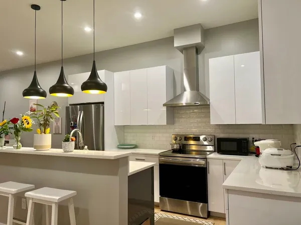 a kitchen with a stove a chandelier and chairs in it