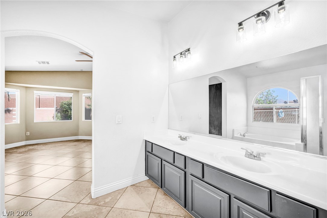 6405 North Raptor Court North Las Vegas, NV 89084 - Photo 37 of 66 A well-lit primary bathroom featuring dual vanities, an inviting soaking tub, and tile flooring.
