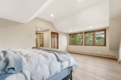 a spacious bedroom with a bed and wooden floor