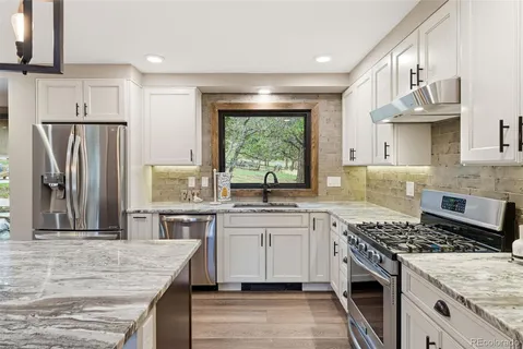a kitchen with stainless steel appliances granite countertop a sink stove refrigerator and cabinets