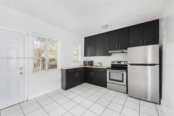 a kitchen with granite countertop a refrigerator and a stove top oven