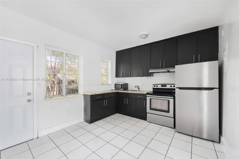 a kitchen with granite countertop a refrigerator and a stove top oven