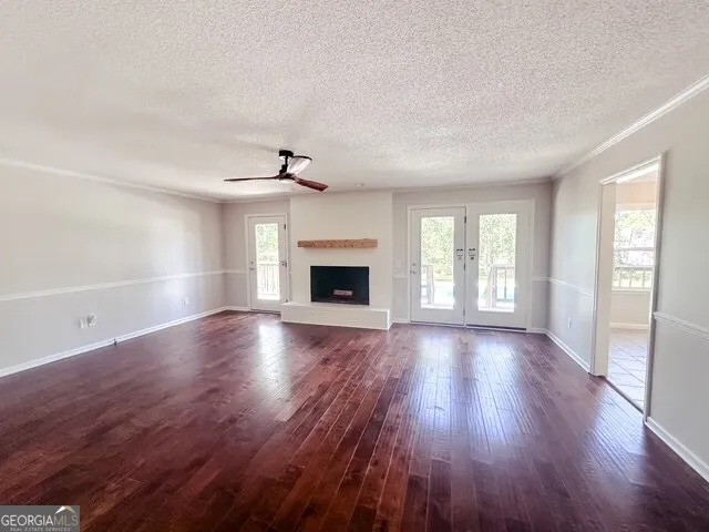 an empty room with wooden floor fireplace and windows