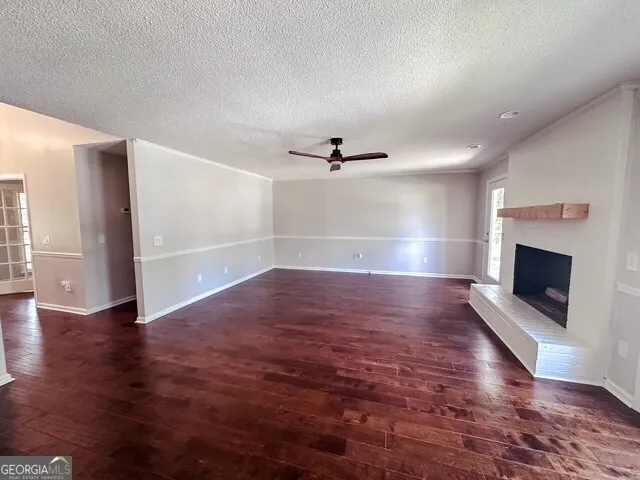 an empty room with wooden floor fireplace and windows