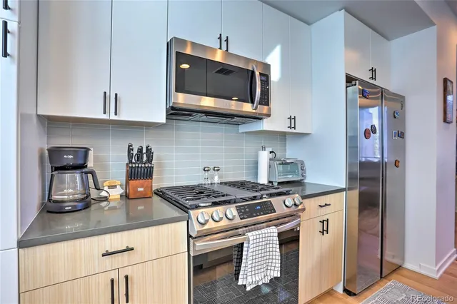 a kitchen with stainless steel appliances granite countertop a stove a sink and a microwave