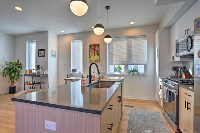 a kitchen with stainless steel appliances granite countertop a sink a stove and a wooden floors
