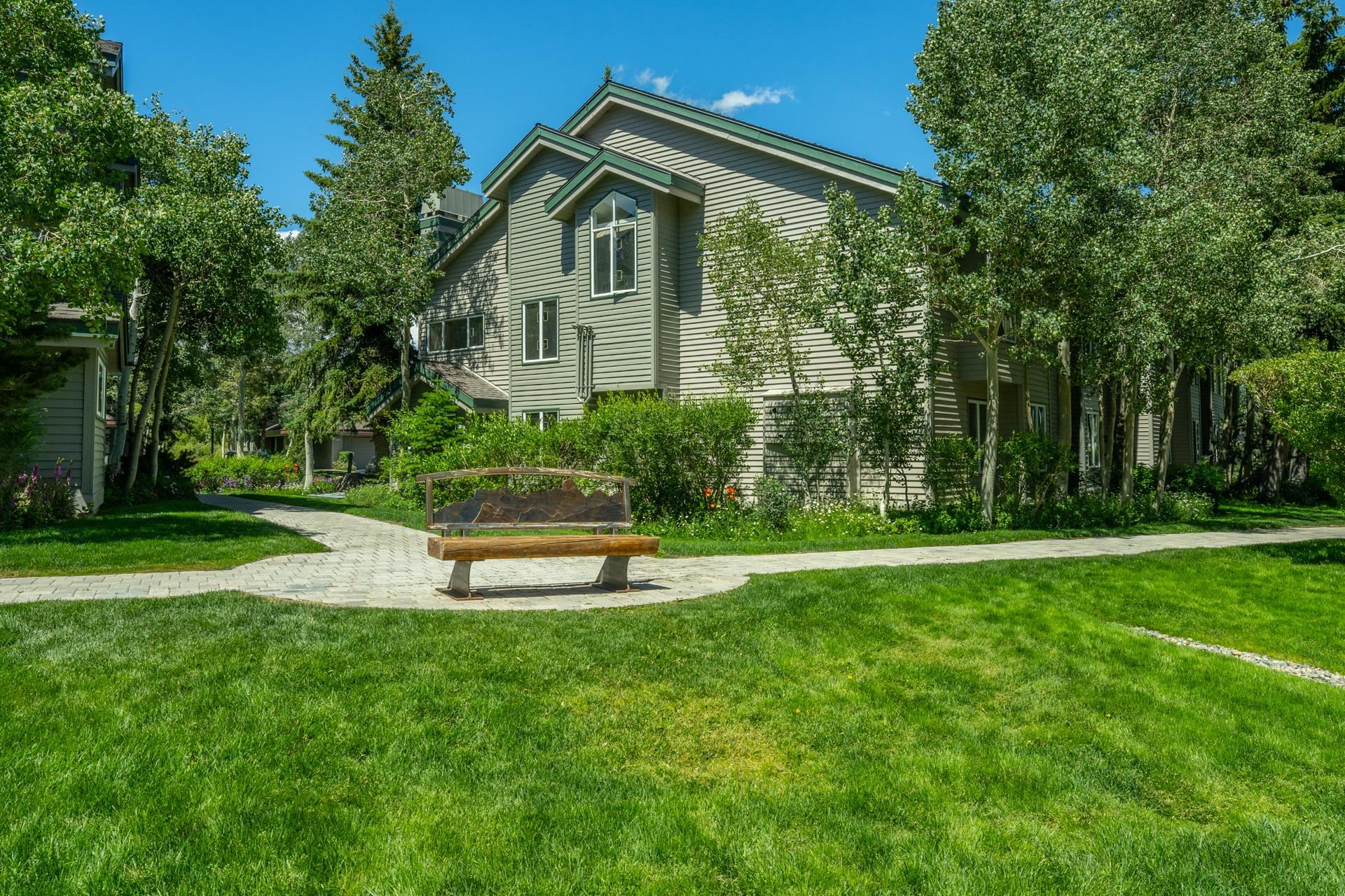 609 Golden Creek Road, Unit 609 Mammoth Lakes, CA 93546 - Photo 35 of 42 Manicured lawn area with a paver pathway, featuring a decorative bench and mature trees