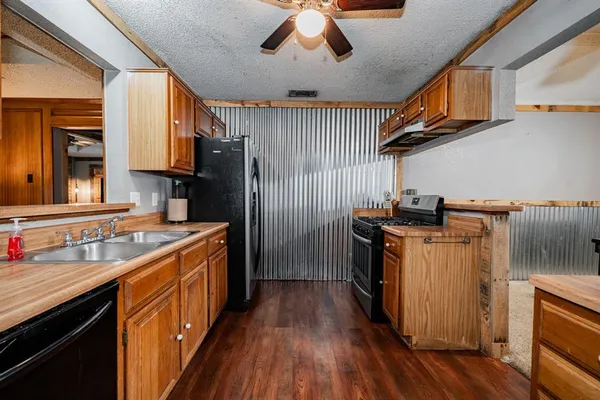 a kitchen with stainless steel appliances granite countertop a stove a sink dishwasher and a refrigerator with wooden floor