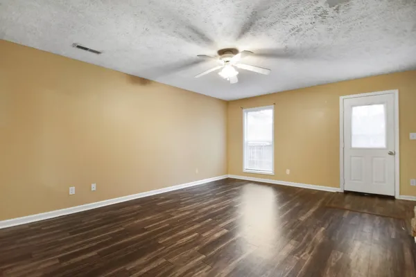a view of an empty room with wooden floor and a window