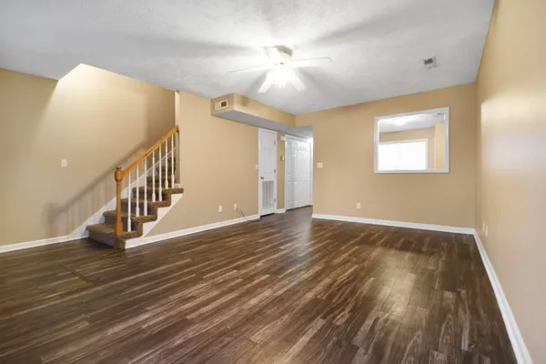 a view of an empty room with wooden floor and a chandelier