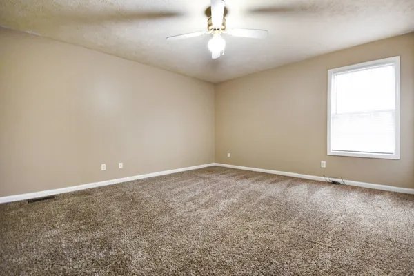 an empty room with a window and a ceiling fan