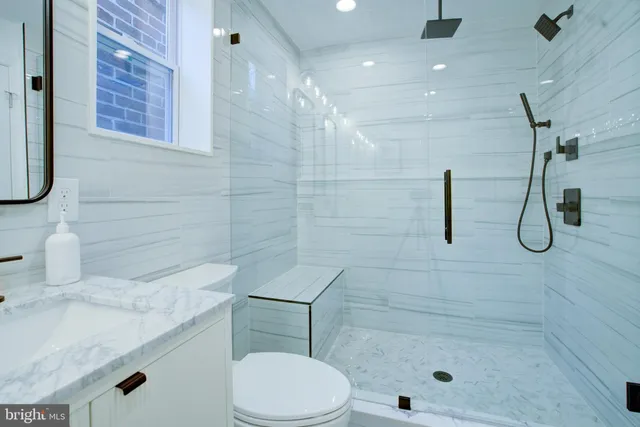 a bathroom with a granite countertop sink a toilet and shower