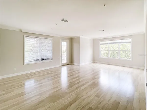 an empty room with wooden floor and windows