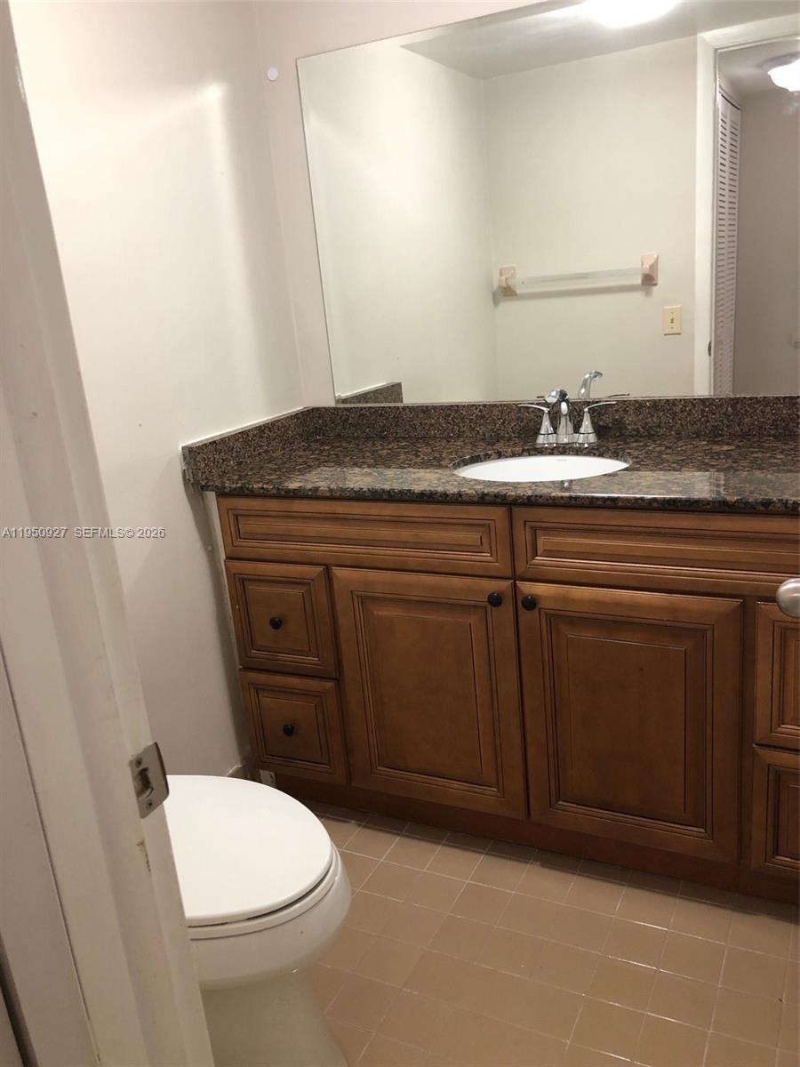 4708 Southwest 67th Avenue, Unit L23 Miami, FL 33155 - Photo 6 of 19 a bathroom with a granite countertop toilet sink and mirror