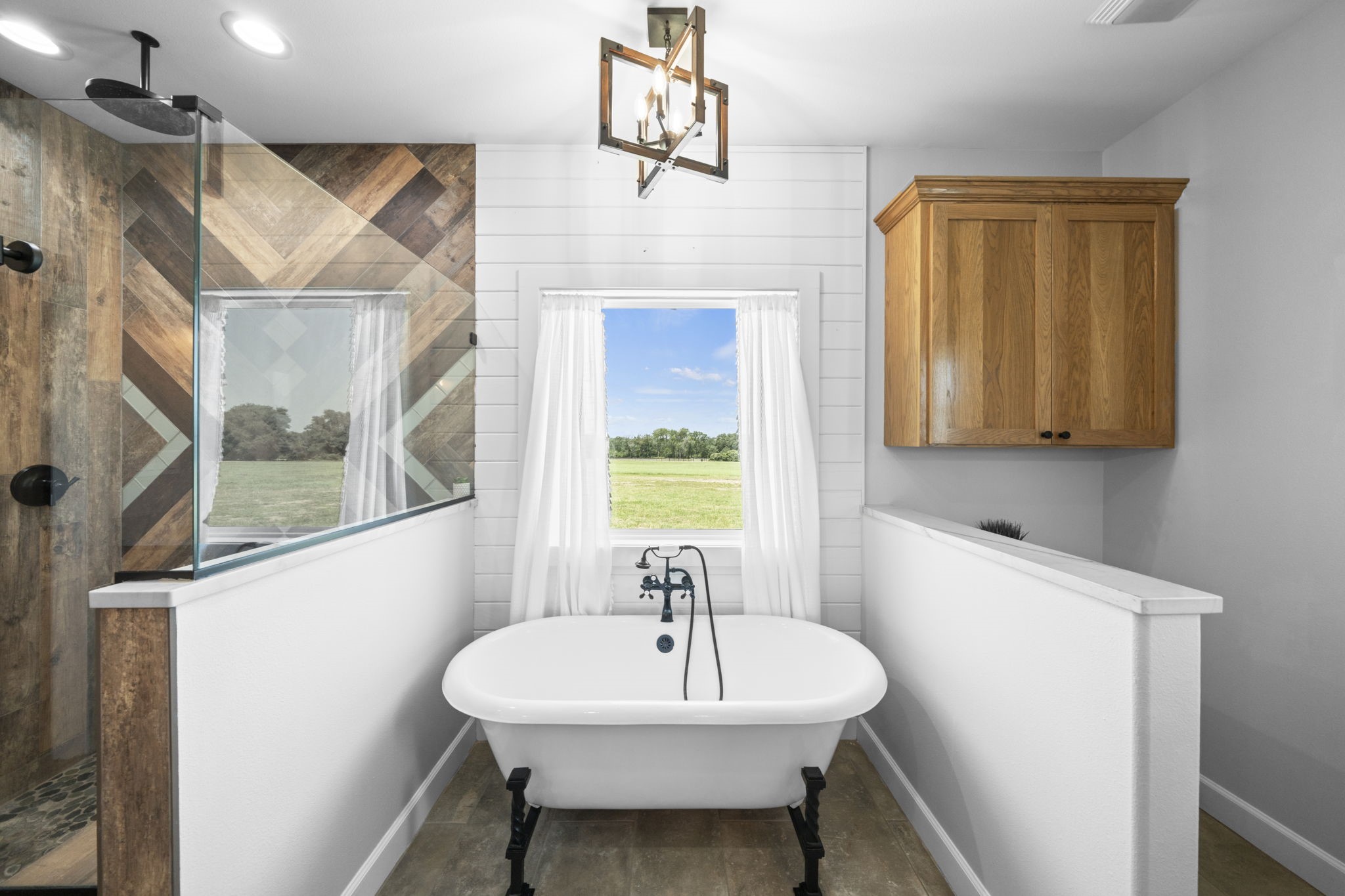 1655 Old Cuero Road Yoakum, TX 77995 - Photo 11 of 24 This spa-inspired primary bathroom offers the perfect place to relax and unwind. A freestanding soaking tub is beautifully positioned beneath a large window, providing peaceful views and abundant natural light.