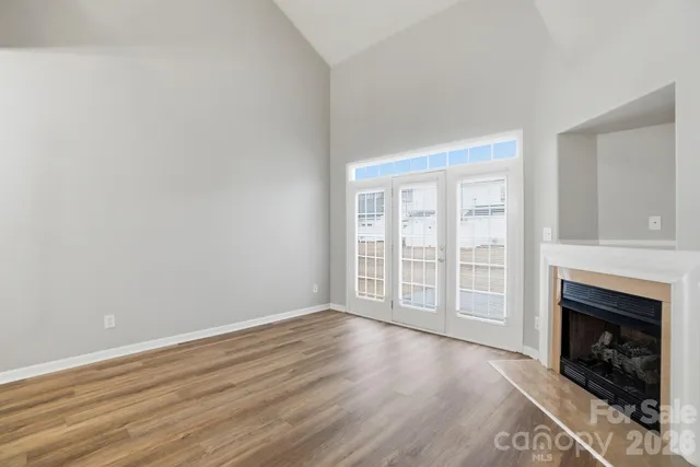 an empty room with wooden floor fireplace and windows