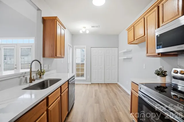 a kitchen with kitchen island granite countertop a sink appliances cabinets and wooden floor
