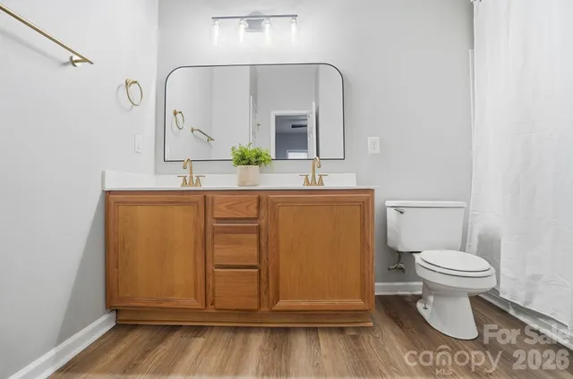 a bathroom with a sink a toilet a mirror and shower