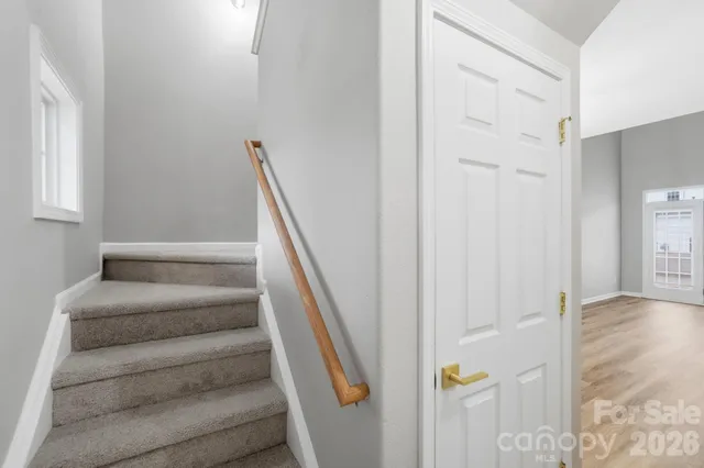 a view of staircase with white walls and white door