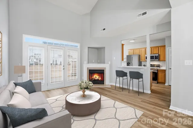 a living room with furniture a fireplace and a kitchen view