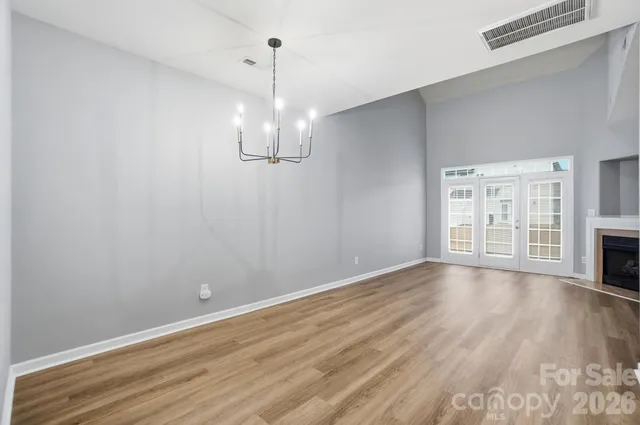 a view of an empty room with wooden floor fireplace and a window