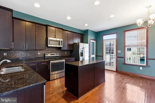 a kitchen with granite countertop wooden floors stainless steel appliances and a window