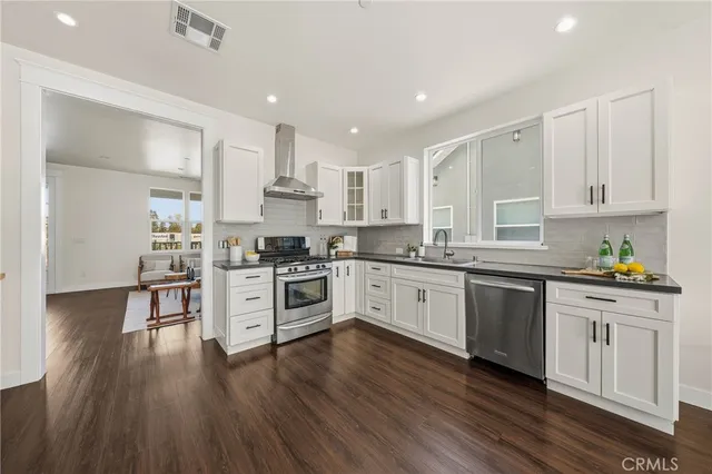 a kitchen with granite countertop wooden floors stainless steel appliances and sink
