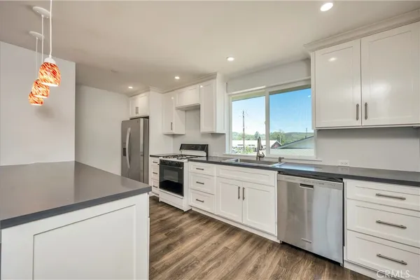 a kitchen with granite countertop a sink a counter space and stainless steel appliances
