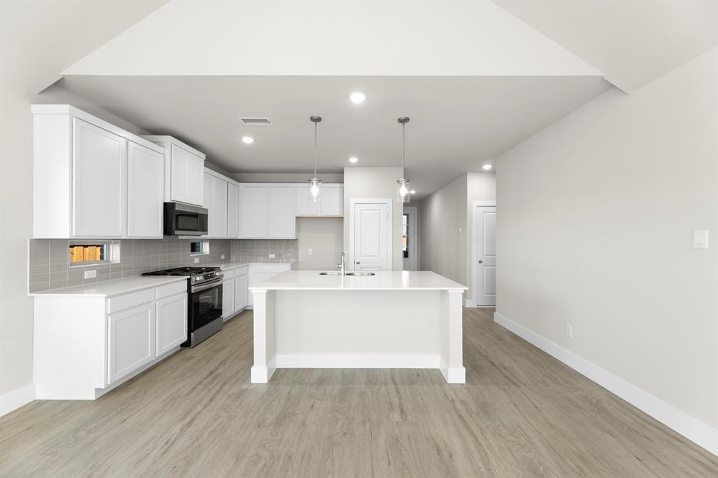 2359 Bell Way Forney, TX 75126 - Photo 6 of 31 a white kitchen with wooden floor and stainless steel appliances