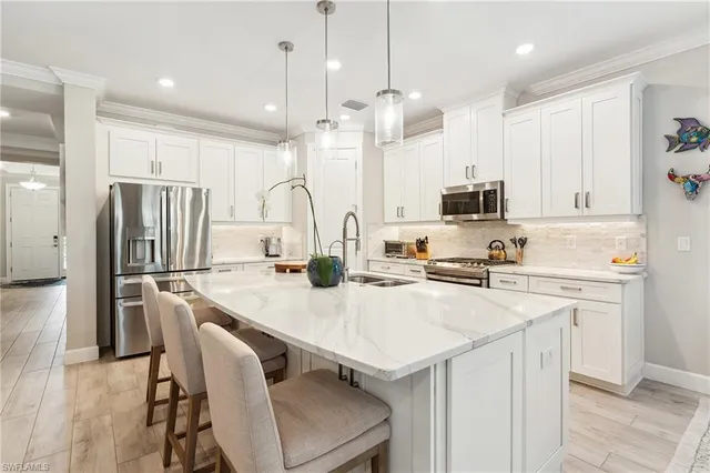 a kitchen with kitchen island a refrigerator a stove a sink and chairs