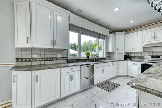 93 South Road Farmington, CT 06032 - Photo 16 of 40 a kitchen with granite countertop white cabinets white appliances a sink and a window