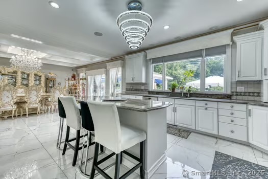 93 South Road Farmington, CT 06032 - Photo 18 of 40 a kitchen with stainless steel appliances granite countertop a sink a stove a dining table and chairs with wooden floor