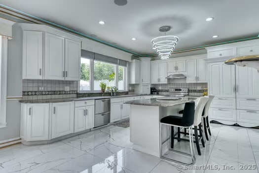 93 South Road Farmington, CT 06032 - Photo 22 of 40 a kitchen with kitchen island granite countertop a table chairs sink and cabinets