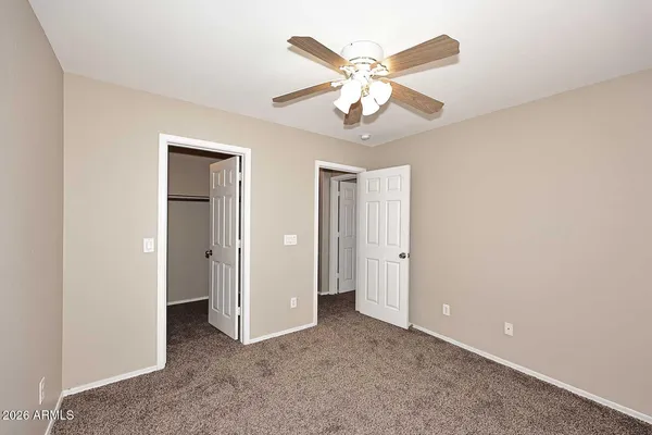 an empty room with a chandelier fan and a bathroom
