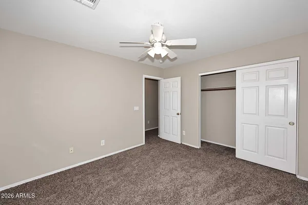 an empty room with closet and a ceiling fan