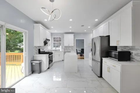 a kitchen with stainless steel appliances a refrigerator a stove a sink a center island and couches