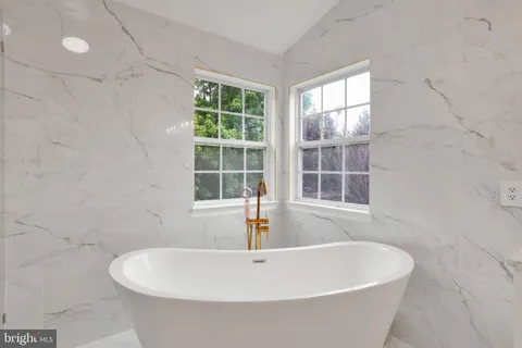 a white bath tub sitting in a bathroom next to a window