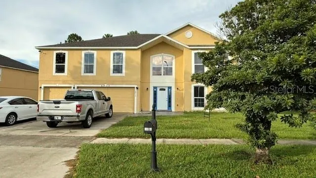 a view of a big house with a big yard and large trees
