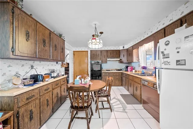 a kitchen with stainless steel appliances kitchen island granite countertop a sink a stove a refrigerator cabinets and chairs