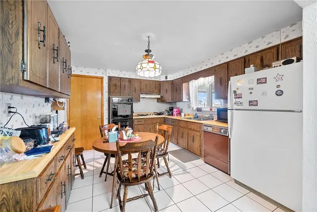 a kitchen with granite countertop a refrigerator a stove a sink dishwasher and white cabinets with wooden floor