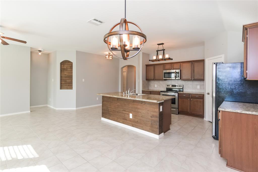 1406 Slate Street Princeton, TX 75407 - Photo 11 of 25 a kitchen with a stove a sink and a refrigerator