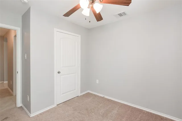 an empty room with a window and a ceiling fan